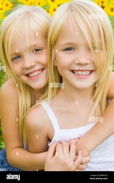 Portrait Of Cute Girl Embracing Her Twin Sister And Both Looking At