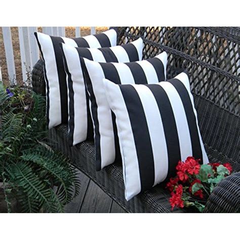 Four Black And White Pillows Sitting On Top Of A Wooden Bench Next To