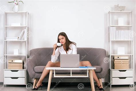 seductive secretary freelancer with legs sit on sofa in office business woman drinking coffee