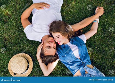 Romantic Couple Of Young People Lying On Grass In Park They Lay On The Shoulders Of Each Other