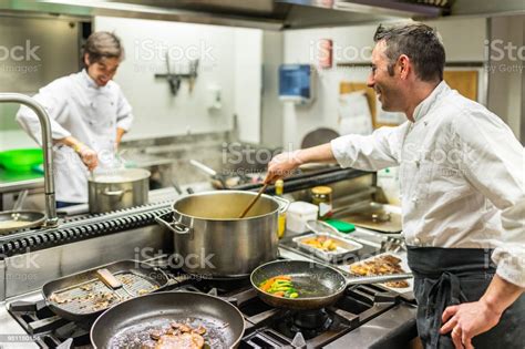 Chef And Cook At Work In A Restaurant Kitchen Stock Photo