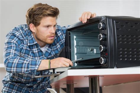 Young Male Repairman Fixing Oven In Kitchen Stock Photo Image Of