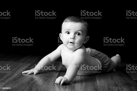 Black White Image Of Baby Lying On Hardwood Floor Stock Photo