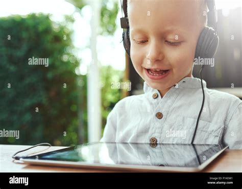 Adorable Little Boy Listening To Recorded Music On His Tablet Computer