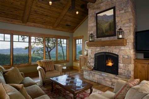 Rustic living room with wood beam ceiling and hardwood flooring topped by a woven rug. Stone Fireplace Surround Ideas - MidCityEast