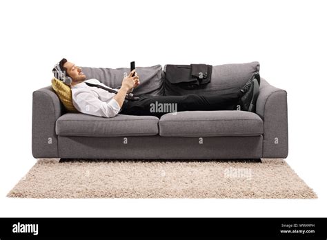 Full Length Shot Of A Businessman Lying On A Sofa And Listening To
