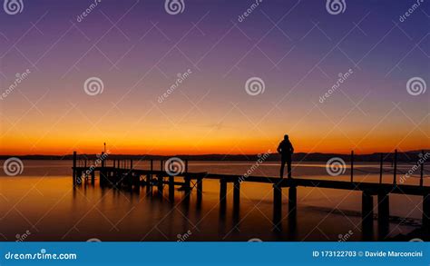 A Man Silhouette Standing On Wooden Pier Lonely At The Sea With