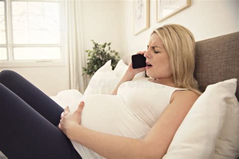 Pregnant Woman On The Bed At Home Having Contractions Holding Cellphone Stock Image Image Of
