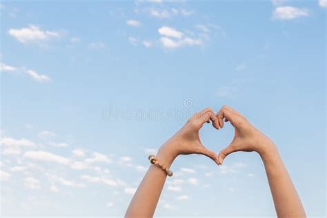 The Woman Lifts Both Her Hands Above Her Head To Make A Heart Symbol That Represents Friendship