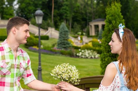 Premium Photo Young Man In Green And Red Plaid Shirt Gives A Girl A Bouquet Of Little White