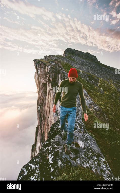 Man Walking Alone On The Edge Mountain Ridge Above Clouds Travel