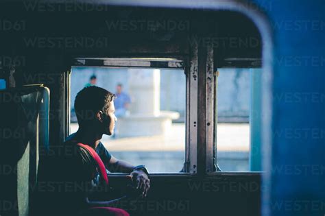 Side View Of Thoughtful Man Looking Through Window In Train Stock Photo