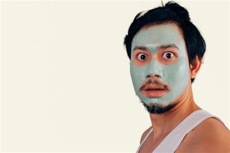 premium photo surprised face of asian man with skin care face mask on isolated background