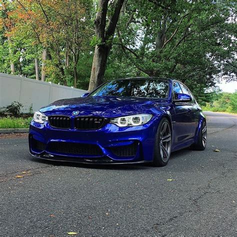 A Blue Bmw Is Parked On The Side Of The Road In Front Of Some Trees