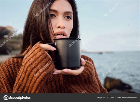 Portrait Of Beautiful Asian Brunette Girl In Knitted Sweater With Mug In Hands Sensually Looking