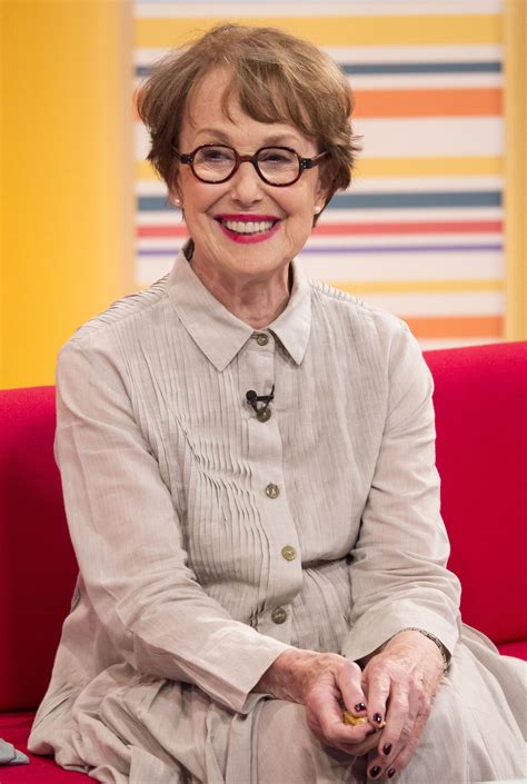 an older woman wearing glasses sitting on a red couch