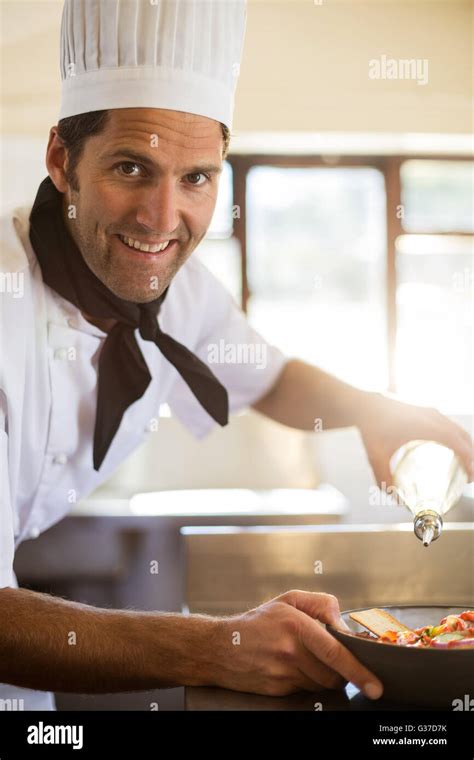 Portrait Of Happy Chef Pouring Olive Oil On Salad Stock Photo Alamy