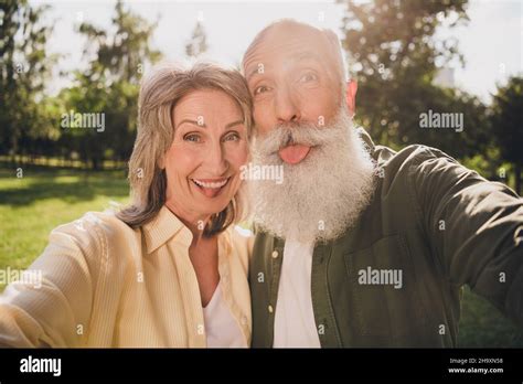 Photo Of Funny Old Couple Do Selfie Tongue Out Wear Shirt Walk In Park
