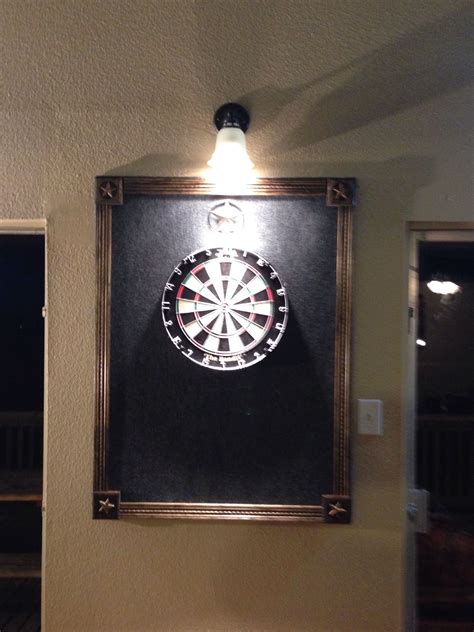 A Dart Board Mounted To The Side Of A Wall Next To A Light On Top Of A