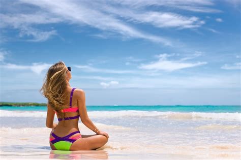 Linda mulher de biquíni na praia tropical a menina senta se na areia