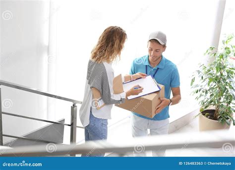 Young Woman Signing Documents After Receiving Parcels From Courier
