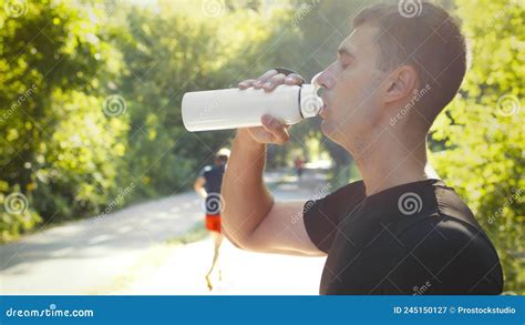 Side View Portrait Of Young Man Jogger Drinking Water Resting During