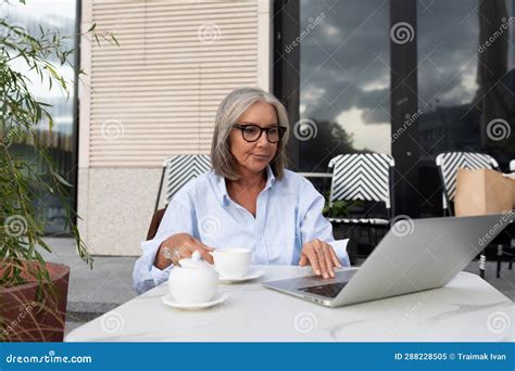 a slender gray haired woman of mature years dressed in a light blue shirt spends a lunch break