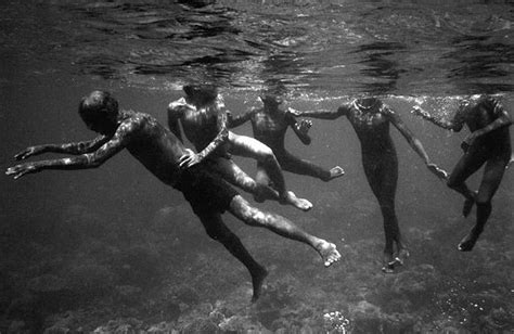 Four People Are Swimming In The Water With Their Backs Turned To The