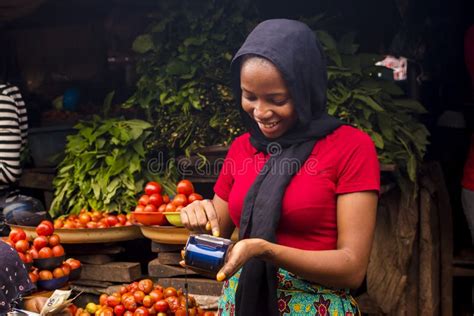 African Woman Selling Food Stuff In A Local Market Smiling While Using