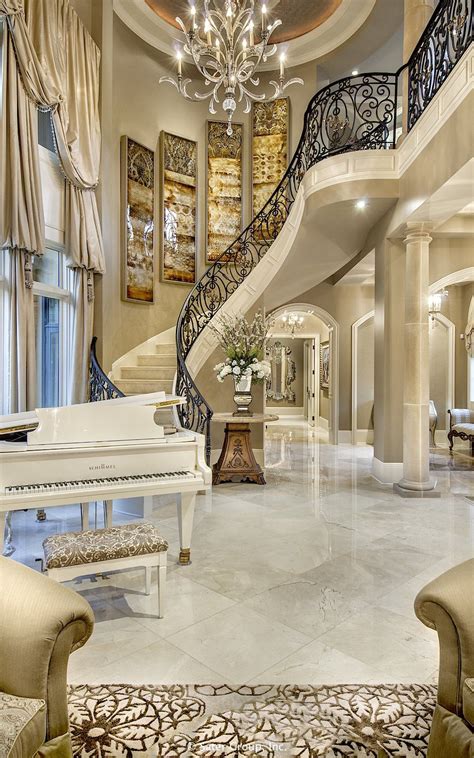 A Grand Piano In The Middle Of A Living Room With Chandelier And Stairs