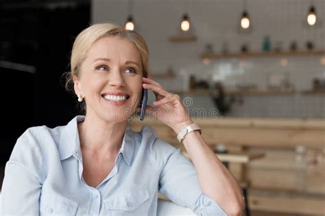 Cheerful Mature Woman Talking On Smartphone And Looking Away Stock