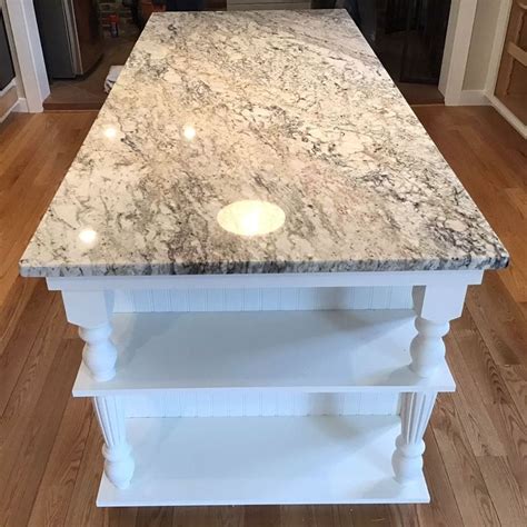 A Kitchen Island With Marble Top And White Cabinets