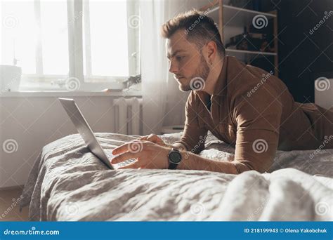 Man Laying At The Stomach At The Bed In Front Of The Laptop And Working