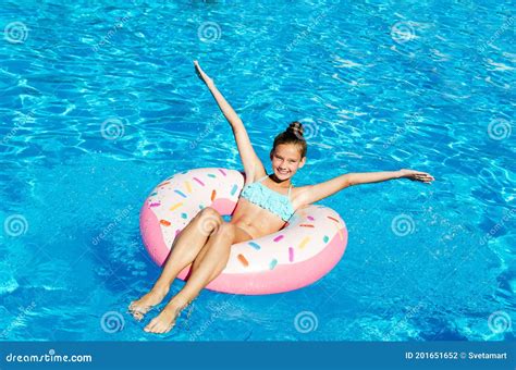 schönes lächelnder mädchen im swimmingpool mit gummiring kind das spaß im urlaub hat stockfoto