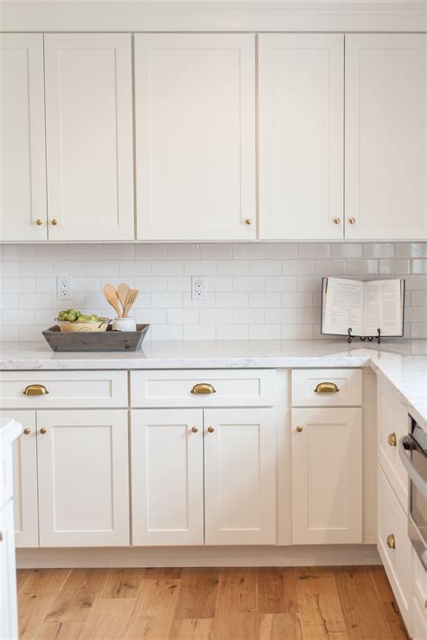 White shaker cabinets black countertops and white stone slab backsplash. White shaker cabinetry with brass cups and knobs - by ...