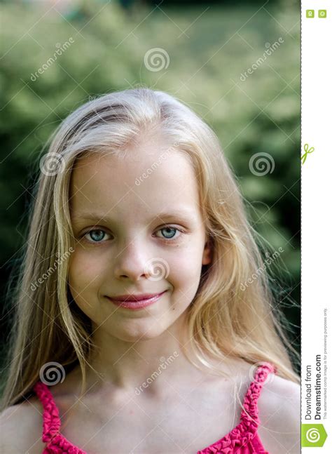 Beautiful little blonde girl smiles winking, posing, touching face with her hands in pink cute dress. Portrait Of A Beautiful Blonde Little Girl With Long Hair ...