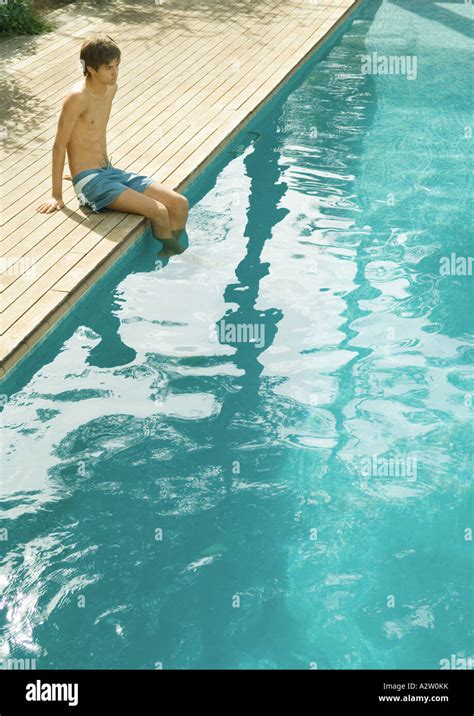 Teenage Boy Sitting On Edge Of Swimming Pool Stock Photo Alamy