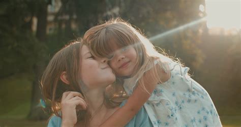 Close Up Of The Cute Small Caucasian Girl Hugging Her Pretty Teen Older Sister While They