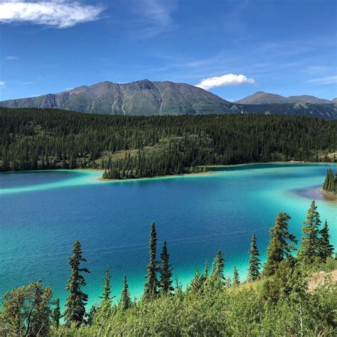 A Blue Lake Surrounded By Trees And Mountains