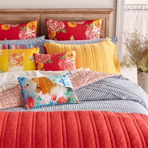 A Bed With Colorful Pillows And Blankets On Its Headboard In A Bedroom
