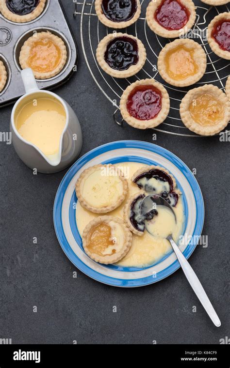 Cooked Homemade Jam Tarts On A Plate With Custard Next To A Baking Tray