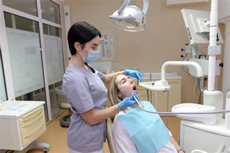 Uma Dentista Feminina Verifica Os Dentes De Uma Jovem Paciente O