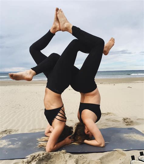 Two Women Doing Yoga On The Beach With Their Hands In Each Other S Pockets