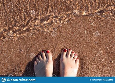 Female Feet With Painted Nails On The Sand In The Water On The Seashore