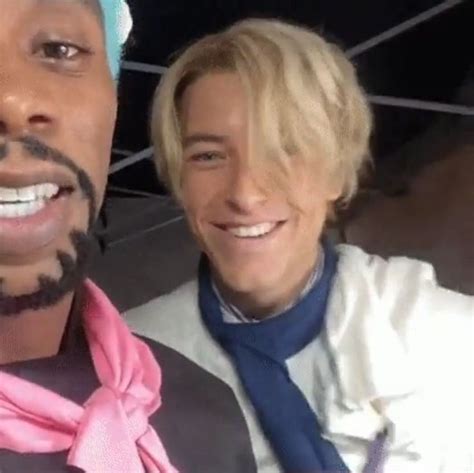 Two Men With Fake Hair And Beards Are Posing For A Selfie In Front Of