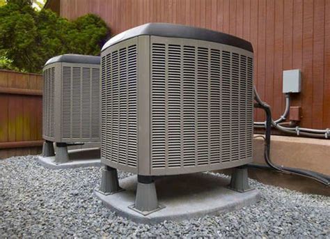 Two Air Conditioners Sitting On Top Of Gravel