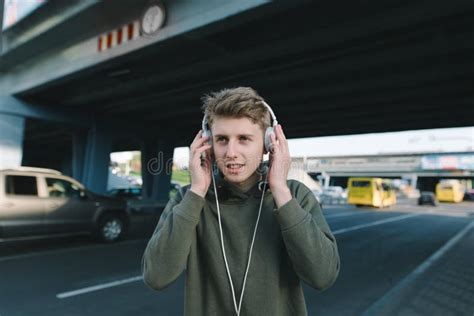 A Positive Young Man Is Listening To Music On The Street In Headphones