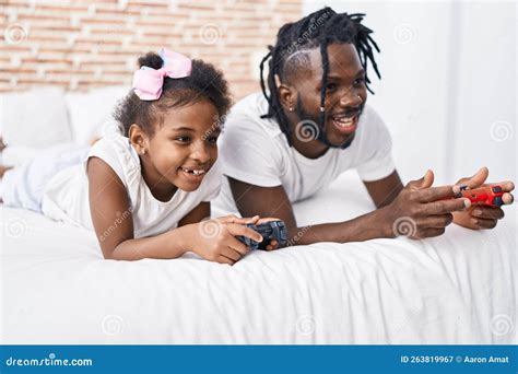 Padre E Hija Jugando Videojuegos Tumbados En La Cama En El Dormitorio