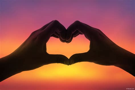 Two Hands Making The Shape Of Love Heart Against Colorful Sky In The