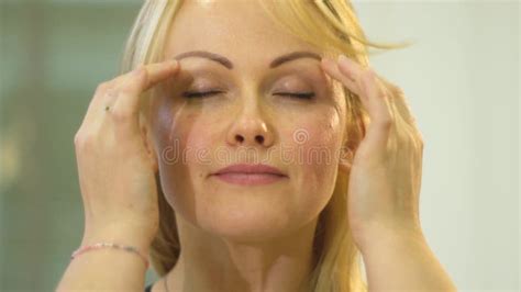 Female Coach In A Blue T Shirt Shows How To Do Head And Face Massage